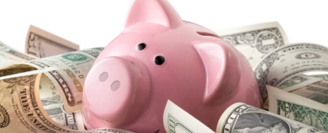 A piggy bank sits amid $100 bills.