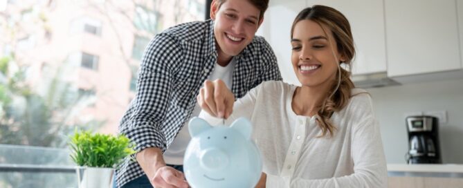 A couple puts some coins into a piggy bank as part of their savings plan.
