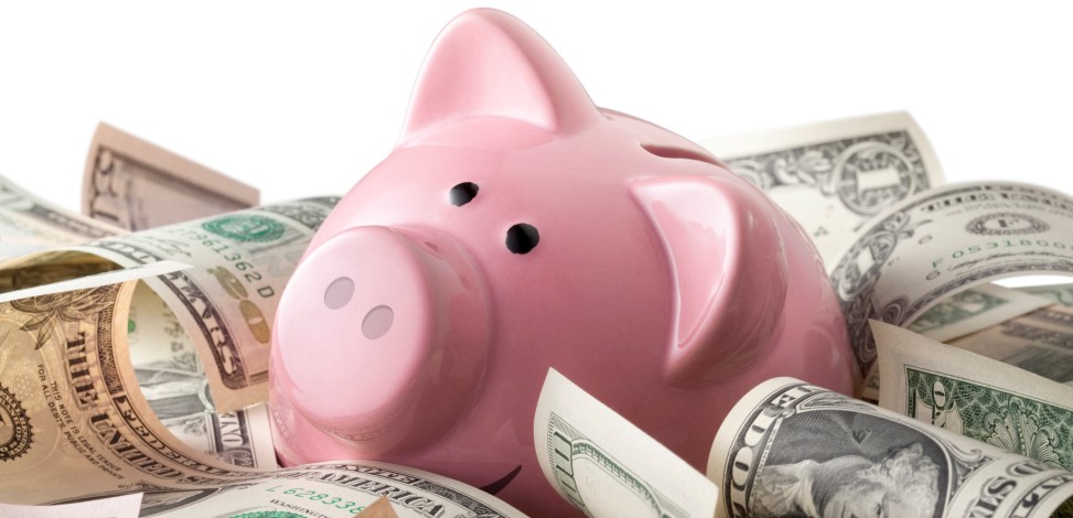 A piggy bank sits amid $100 bills.
