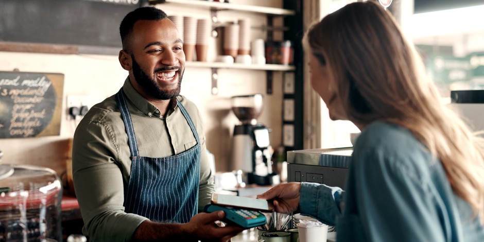 A woman pays for her coffee from her digital wallet on her phone.